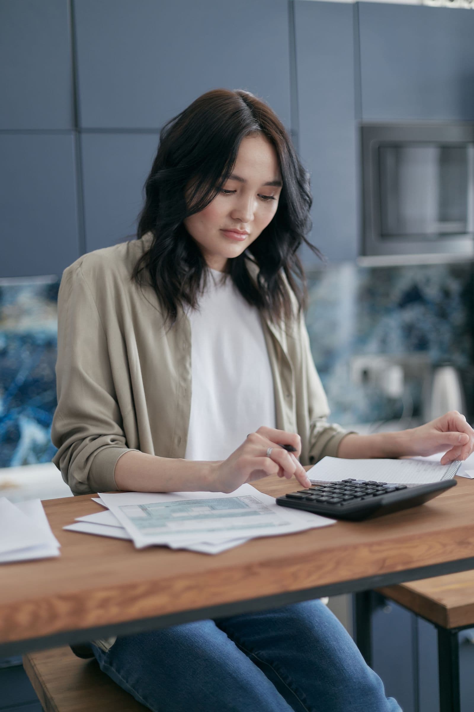 Woman reviewing household bills with a calculator