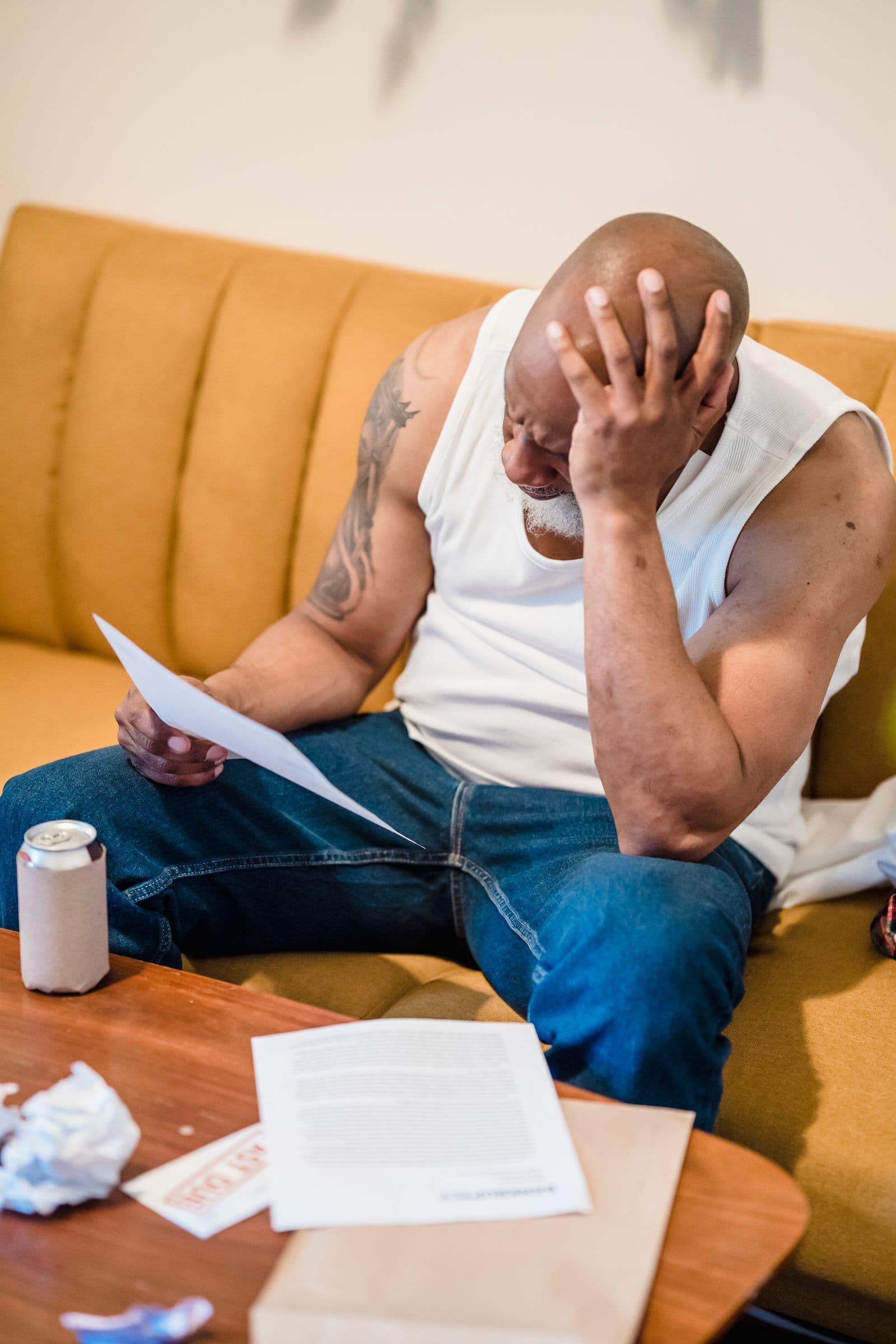 Man holding his forehead while reviewing bills at home