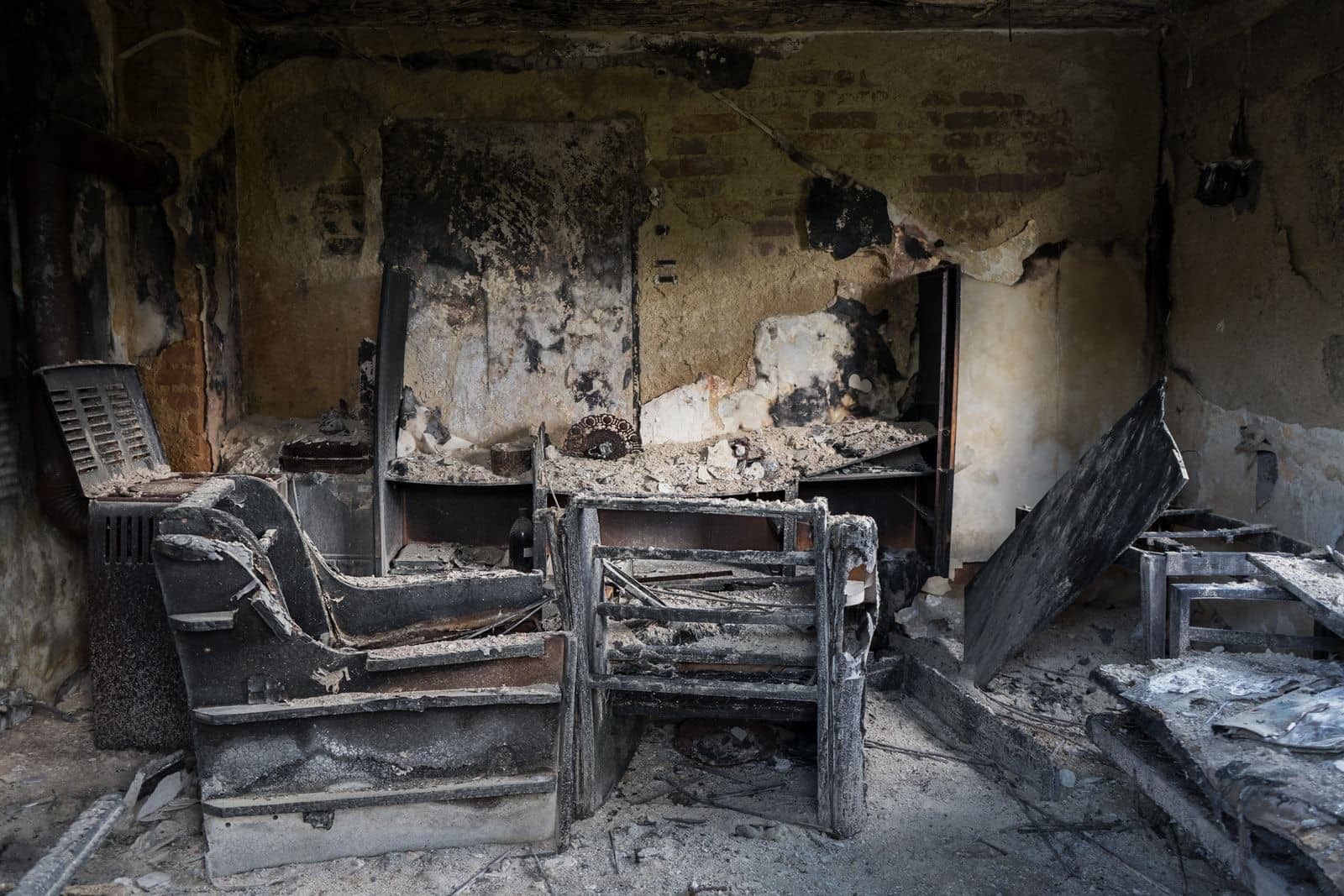 Charred furniture and smoke-blackened walls inside a fire-damaged room