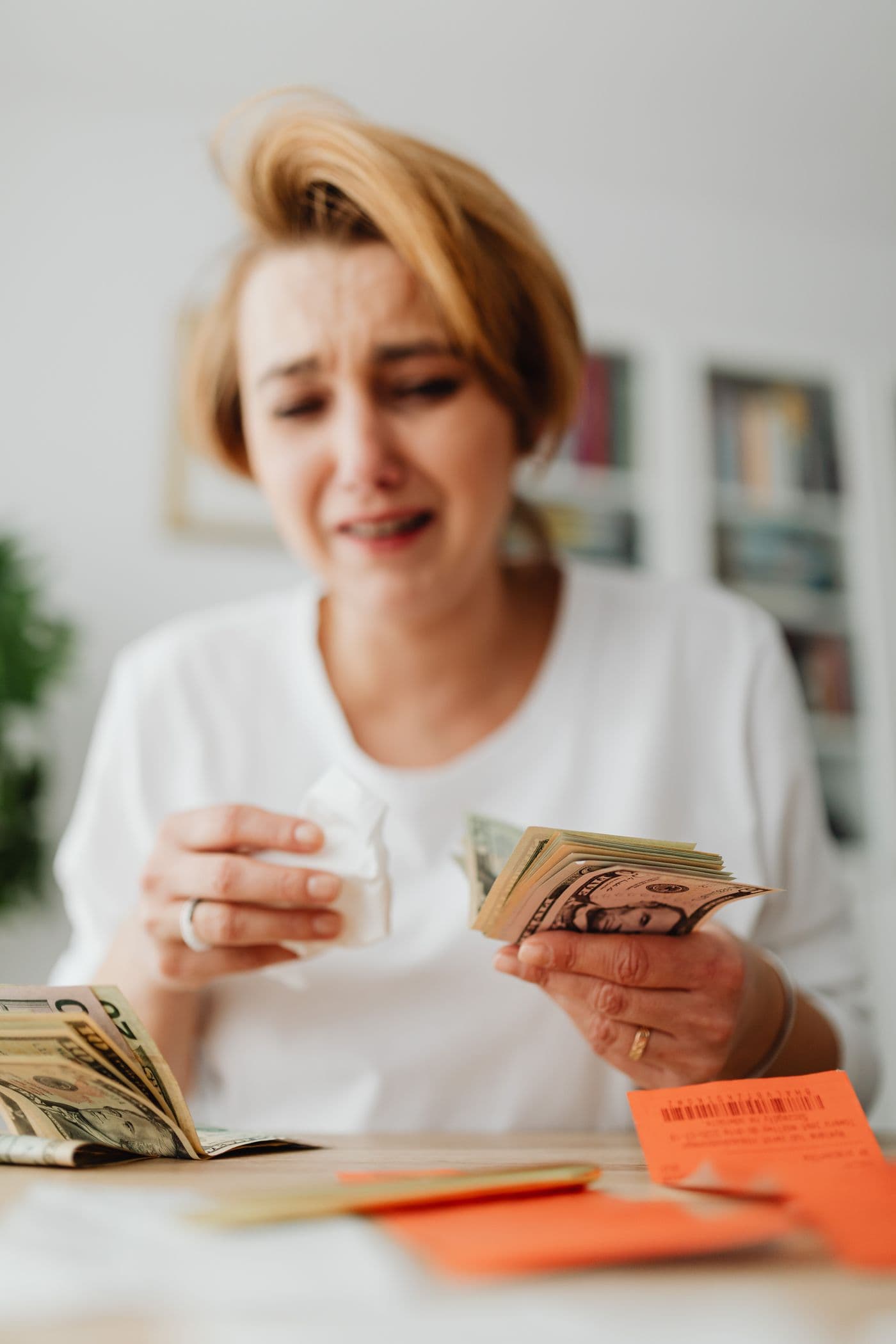 Woman comparing household bills and cash at home